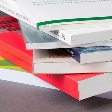 Stapel Bücher mit Klebebindung vor grauem Hintergrund