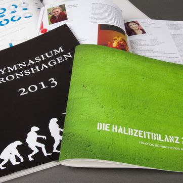 Broschüren und Flyer in Digitaldruck gedruckt vor grauem Hintergrund 